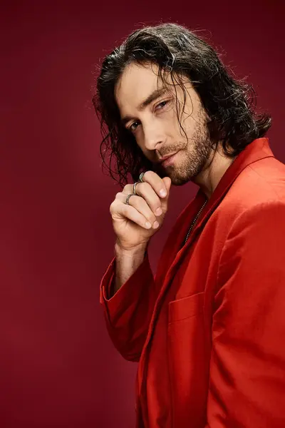 Красивий чоловік у червоній сорочці, що демонструє вражаюче довге волосся у впевненій позі. — стокове фото
