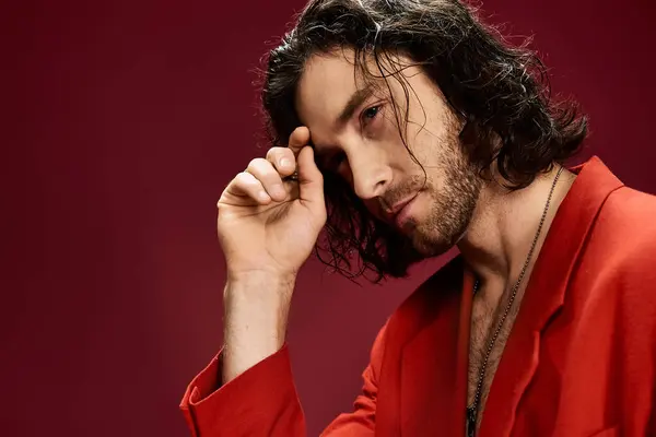 A handsome man with flowing hair strikes a pose in a vibrant red jacket. — Stock Photo