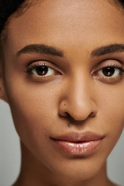 Nahaufnahme einer jungen Afroamerikanerin mit auffallend braunen Augen, die sich auf ihre Hautpflege konzentriert. — Stockfoto