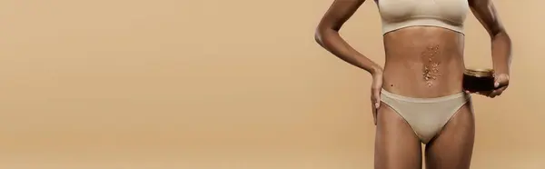 African American woman looking chic in a bikini, posing against a beige background. — Stock Photo