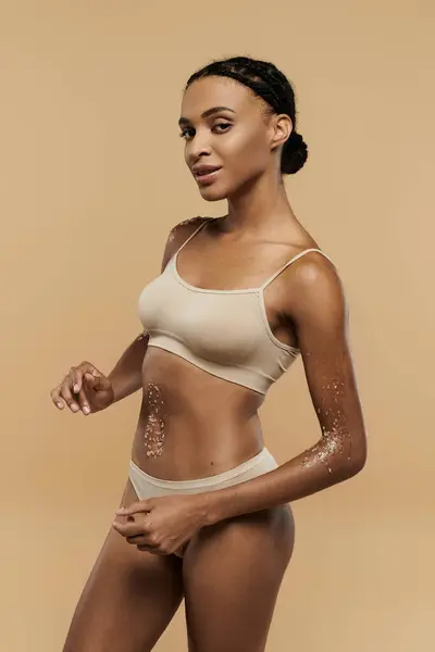 African American woman flaunting a bikini top and panties with grace and confidence on a neutral background. — Stock Photo