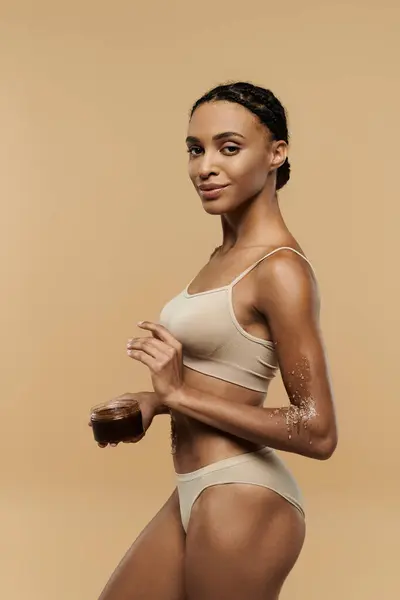 Una bella donna afroamericana in bikini con uno scrub su uno sfondo beige. — Foto stock