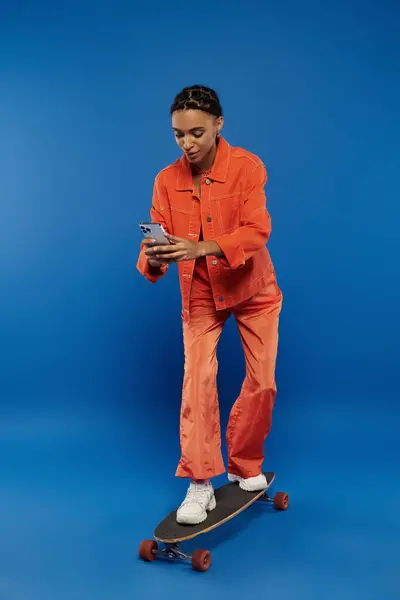A woman in an orange jumpsuit skillfully rides a skateboard. — Stock Photo