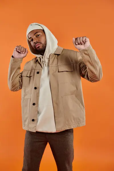 African American man in jacket and hoodie striking a pose against vibrant backdrop. — Stock Photo