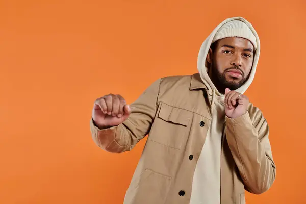 An African American man in a hoodie striking a stylish pose against a vibrant backdrop. — Stock Photo