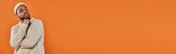 Stylish African American man posing in front of vibrant orange backdrop. — Stock Photo