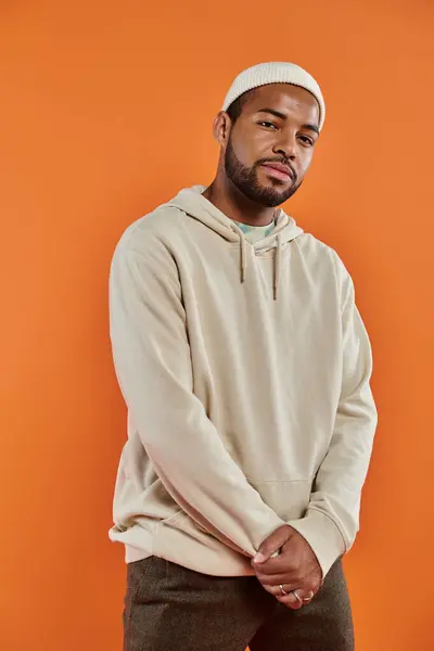 Stylish African American man posing in front of vibrant orange backdrop. — Stock Photo