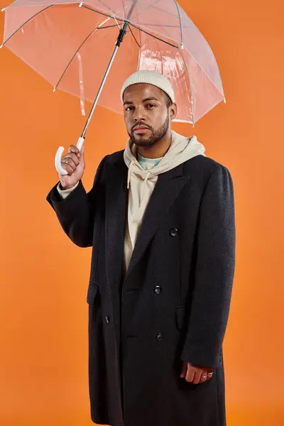 Afroamerikaner in Mantel und Hut mit Regenschirm. — Stockfoto