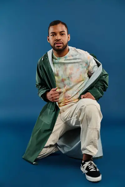 A stylish African American man sitting boldly in a vibrant green coat. — Stock Photo
