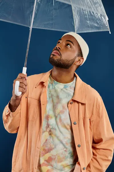 Homme élégant tient parapluie clair sur fond bleu. — Photo de stock