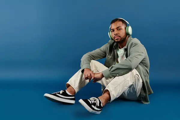 A man sitting on the ground while wearing headphones. — Stock Photo