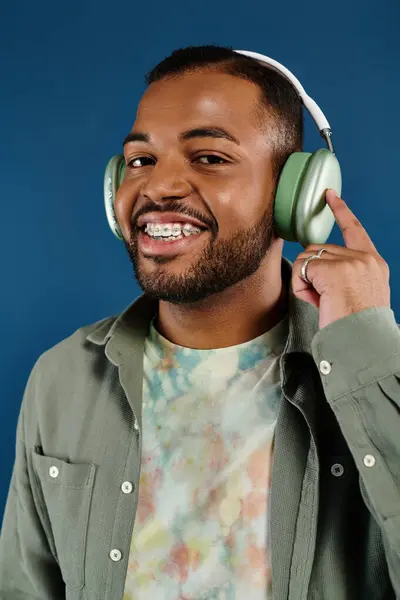 Hombre sonriente con auriculares en un vibrante telón de fondo. - foto de stock