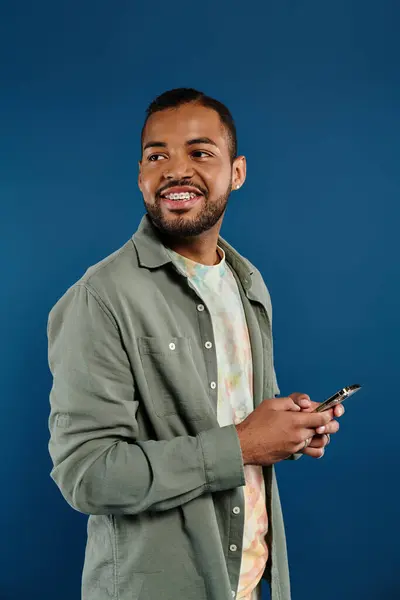 African American man smiling, holding cell phone. — Stock Photo