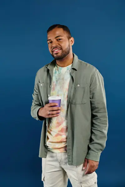 African American man enjoying coffee against blue backdrop. — Stock Photo