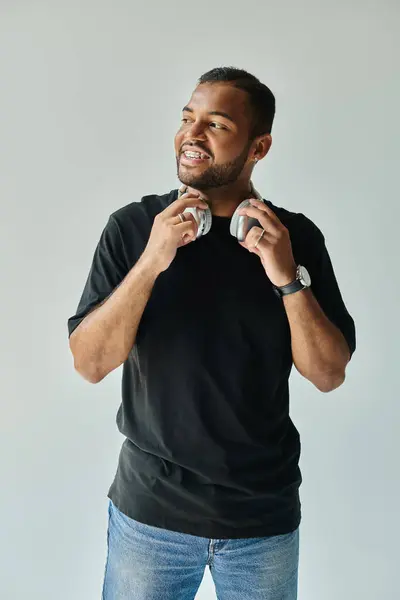 Stylish African American man holds headphones against vibrant backdrop. — Stock Photo