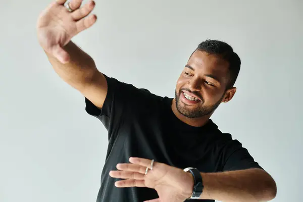 Stylish African American man gracefully raises hands against vibrant backdrop. — Stock Photo