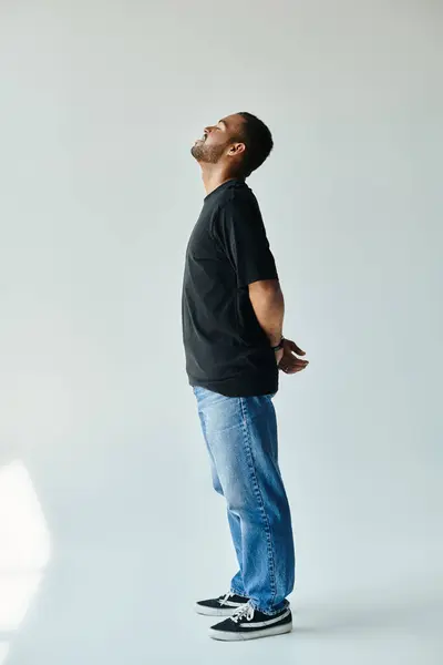 A stylish African American man stands with hands in pockets against a vibrant backdrop. — Stock Photo