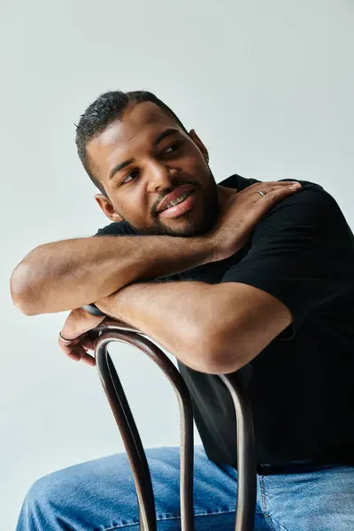 Stylish African American man sitting on chair with crossed arms. — Stock Photo