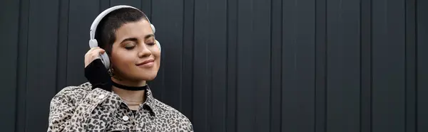 A young woman with short hair and a leopard print jacket, wearing headphones — Stock Photo