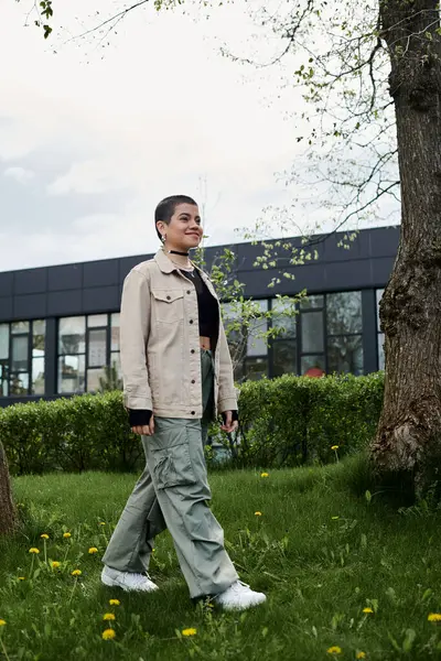 A woman leisurely walks through a lush green field, accompanied only by a majestic tree. — Stock Photo