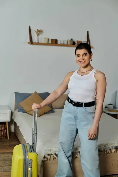 Young woman with short hair standing next to a yellow suitcase, packing for a vacation and trip. — Stock Photo