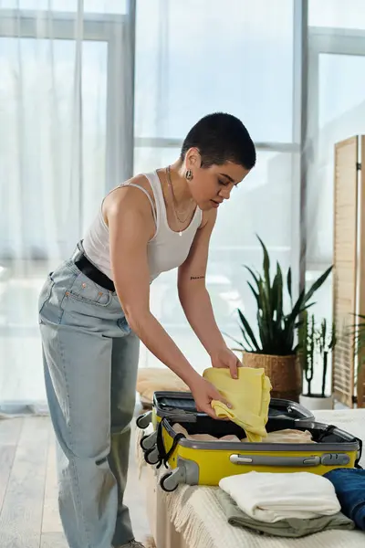 Eine junge Frau mit kurzen Haaren, die sich akribisch auf einem Bett in einem gemütlichen Zimmer auf ihre bevorstehende Reise vorbereitet. — Stockfoto
