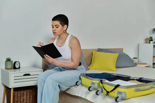 Eine Frau entspannt sich auf einem Bett, vertieft in eine Notiz in der Nähe von Gepäck — Stockfoto