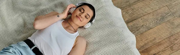 A man in casual wear lies on a bed, engrossed in music — Stock Photo