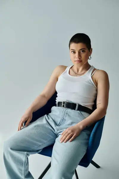 A young woman with short hair sits elegantly in a chair in a relaxed and composed posture. — Stock Photo