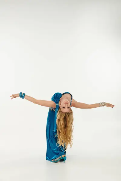Woman in blue dress gracefully executes a handstand. — Stock Photo