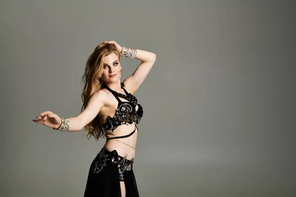 Mujer elegante mostrando danza del vientre en llamativo traje negro y plata. - foto de stock