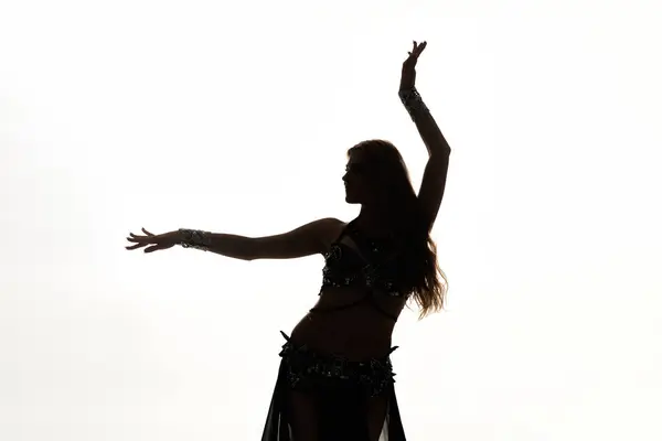 A woman in a belly dance pose with her arms raised gracefully. — Stock Photo