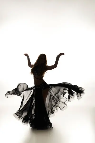 A mesmerizing woman in a black dress gracefully dances. — Stock Photo