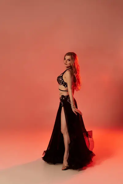 A captivating woman in a black dress strikes a pose exuding elegance and grace. — Stock Photo