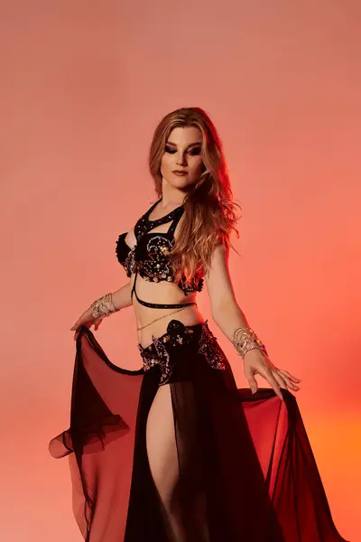Young woman in captivating black and red attire, gracefully dancing a mesmerizing belly dance. — Stock Photo
