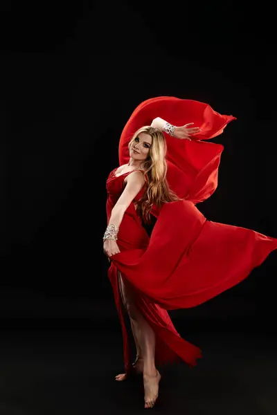 Uma jovem cativante em um vestido vermelho executa uma dança hipnotizante. — Fotografia de Stock