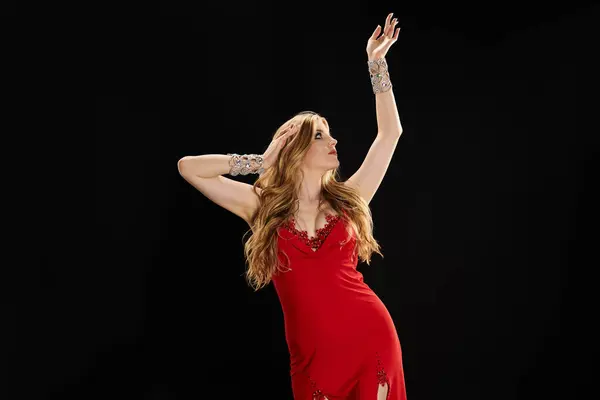 Young woman in red dress gracefully dancing with hands raised. — Fotografia de Stock
