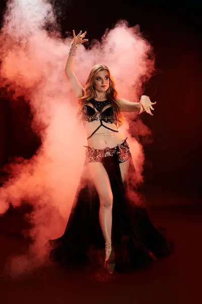 Una donna ipnotizzante balla con grazia in un abito da danza del ventre. — Foto stock