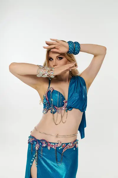 Young woman captivatingly executes belly dance routine in blue costume. — Stock Photo