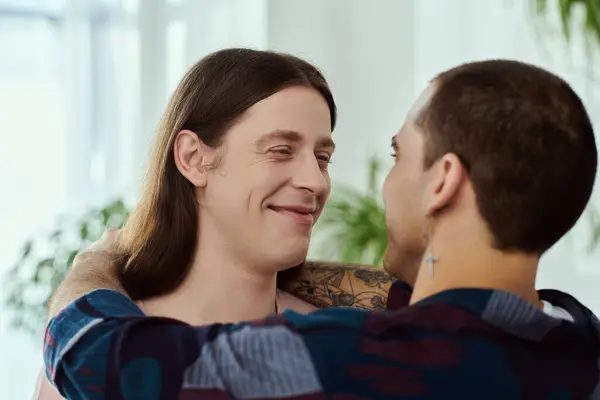 A gay couple, hugging in casual clothes in a warmly lit room. — Stock Photo