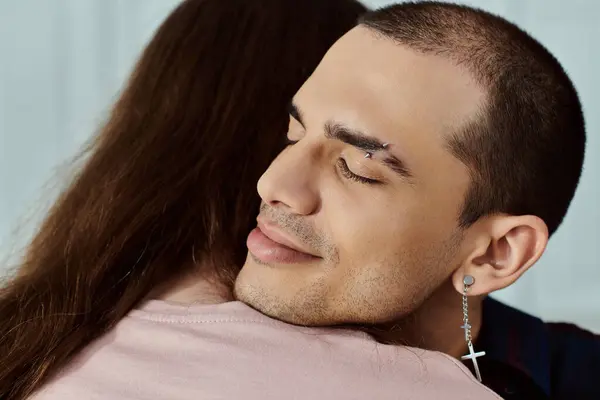 A close-up of a man, part of a gay couple, wearing a cross earring, expressing a sense of spiritual depth. — Stock Photo