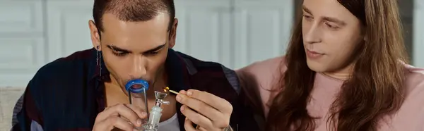 A gay couple in casual attire, together at home, man lighting marijuana in the glass bong — Stock Photo