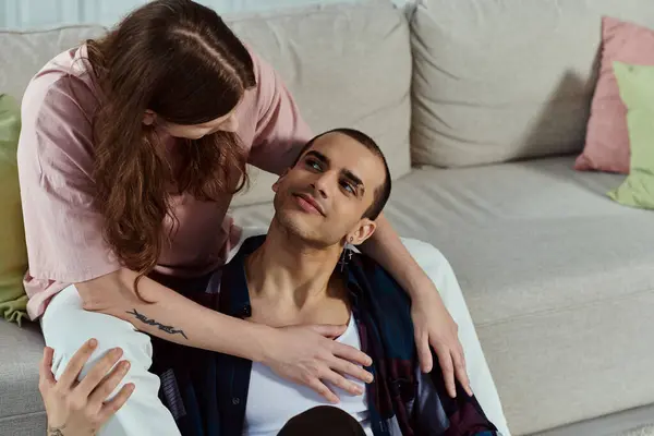 Ein Mann sitzt auf einer Couch und teilt einen friedlichen Moment mit einem Partner neben sich in einem gemütlichen Zuhause-Ambiente. — Stockfoto