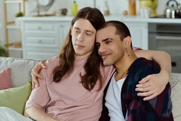 A gay couple in casual clothes sit closely on a couch, enjoying quality time together at home. — Stock Photo