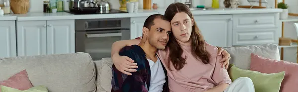 A gay couple, sitting closely together on a comfortable couch, sharing a moment of love and togetherness. — Stock Photo