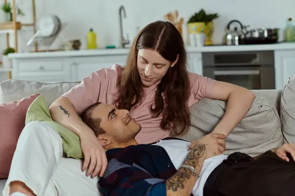 A casual, happy gay couple relaxes on a comfy couch in their home, enjoying each others company. — Stock Photo