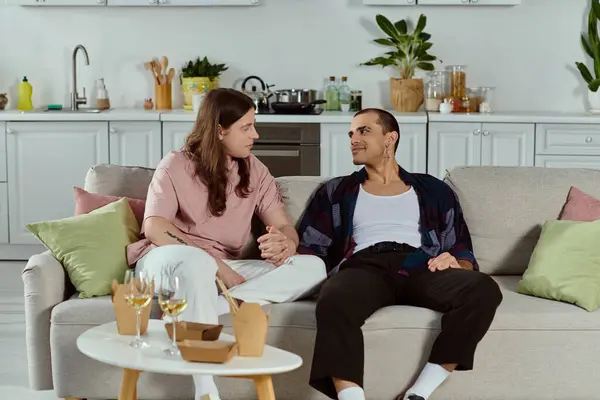 A gay couple in casual clothes having a deep conversation while sitting comfortably on a couch at home. — Stock Photo