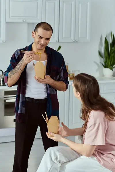A gay couple, are happily eating food in a cozy kitchen setting. — Stock Photo