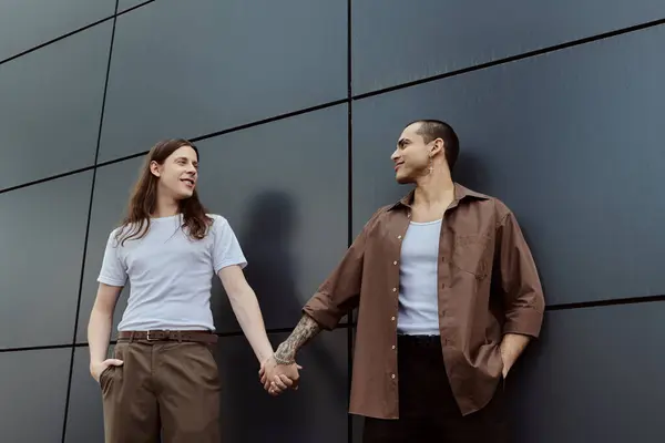 A gay couple standing side by side, holding hands in a show of unity and love outdoors. — Stock Photo