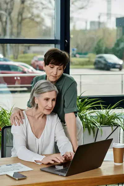 Un couple axé sur le travail sur un ordinateur portable à une table. — Photo de stock